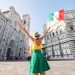 Young female traveler standing with italian flag in front of the famous Santa Maria del Fiore cathedral in Florence. Promoting tourism in Italy